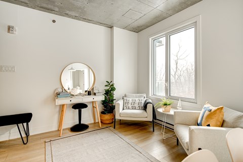 a living room with white furniture and a mirror and a window